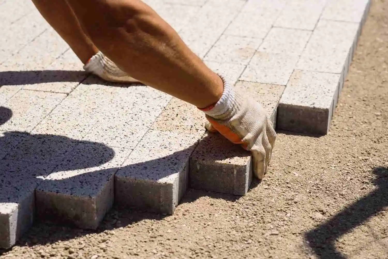 Worker carefully placing paving stones during a DIY vs hiring a professional paver installation.