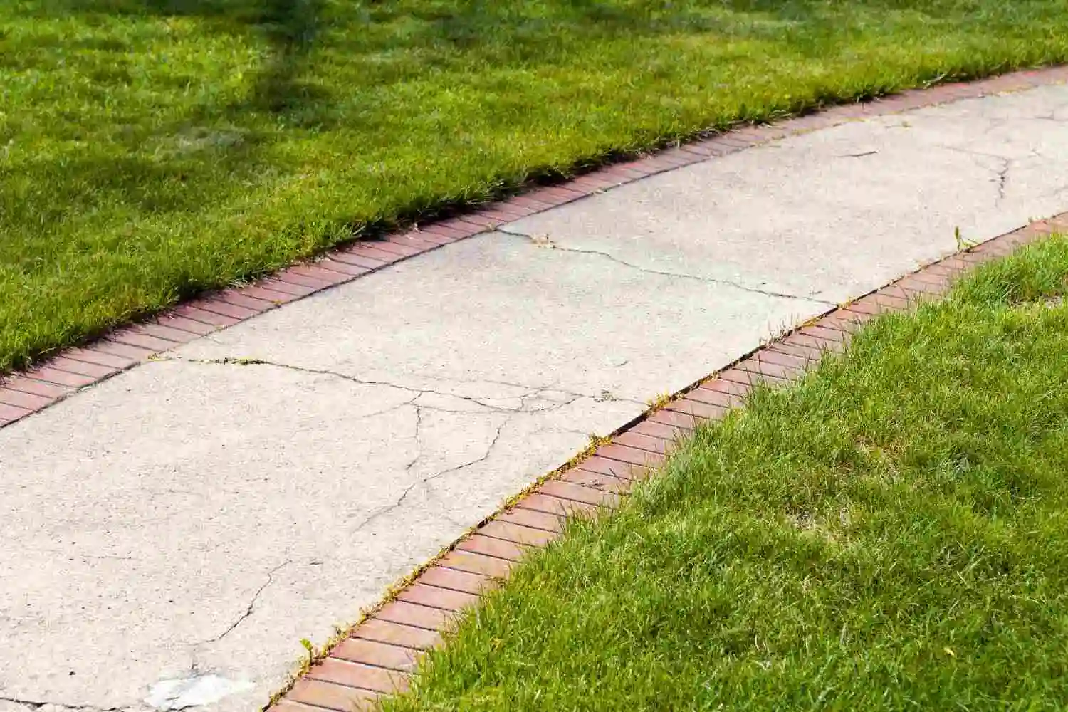 Concrete walkway framed with red brick borders, demonstrating what are sidewalks made of in residential areas.