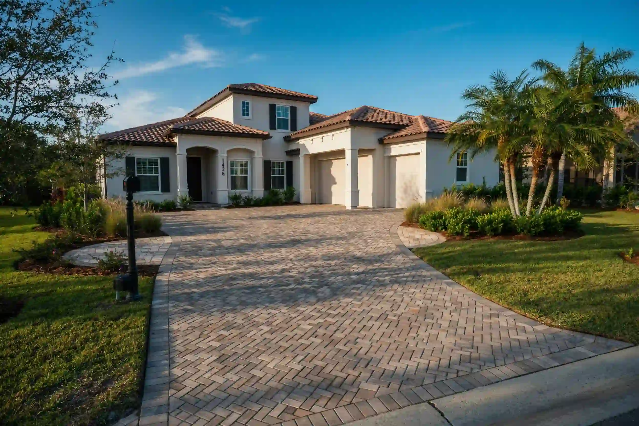Herringbone paver driveway with curved walkway and border in front of a two-story stucco home